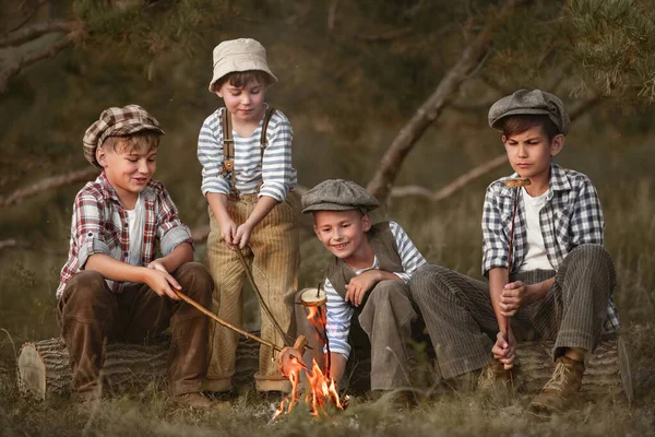 夏の夜に森の中でソーセージとパンを炒める少年たち — ストック写真