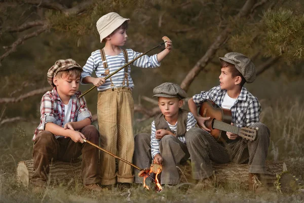 夏天的傍晚 男孩子们在树桩边的树林里煎香肠 — 图库照片
