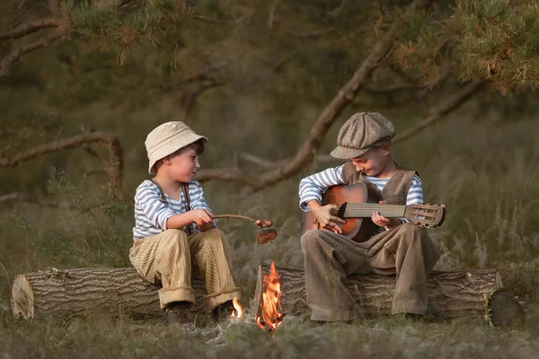 Boys fry sausages in the woods at the stake on a summer evening