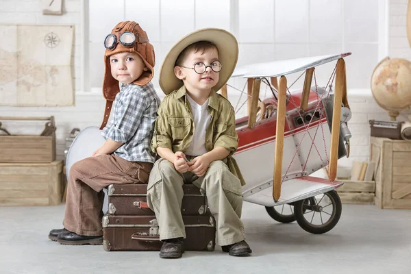 两个小男孩把自己想象成一名飞行员和一名游客 在房间的飞机旁边玩耍 — 图库照片
