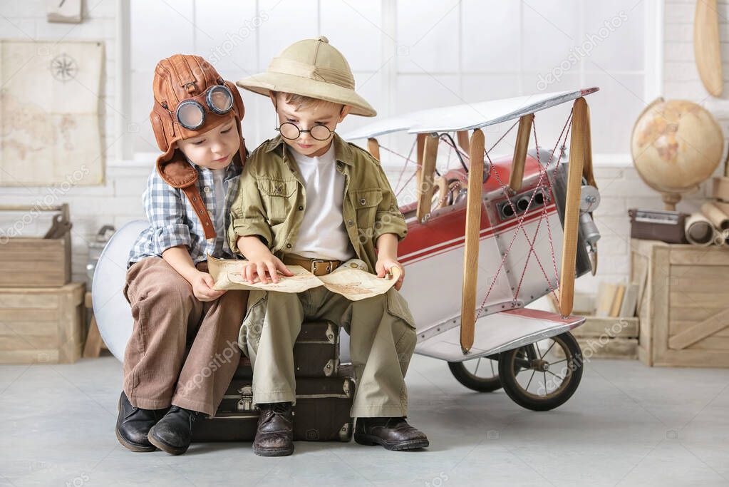 Two little boys imagine themselves as a pilot and a tourist and solve a map near the plane.
