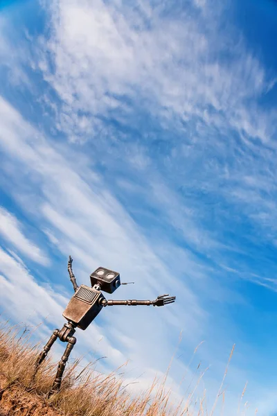 Robot with arms raised looks up at the sky