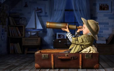 Küçük çocuk kendini turist olarak hayal ediyor ve odasında oynuyor.