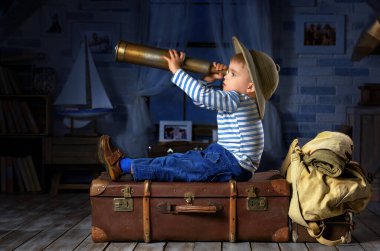 Küçük çocuk kendini turist olarak hayal ediyor ve odasında oynuyor.