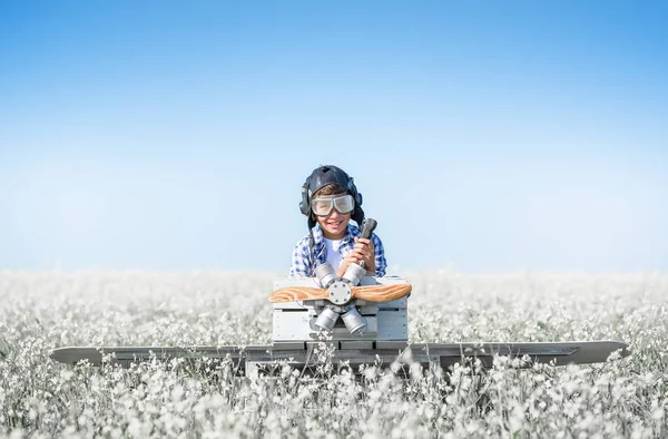 Young aviator with a model airplane in the field on a sunny day
