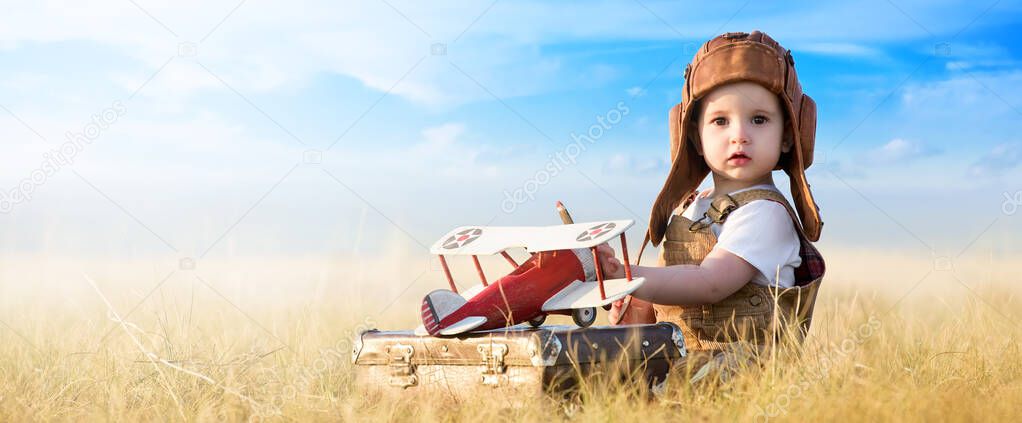 Young aviator with model airplane in the field on a sunny day