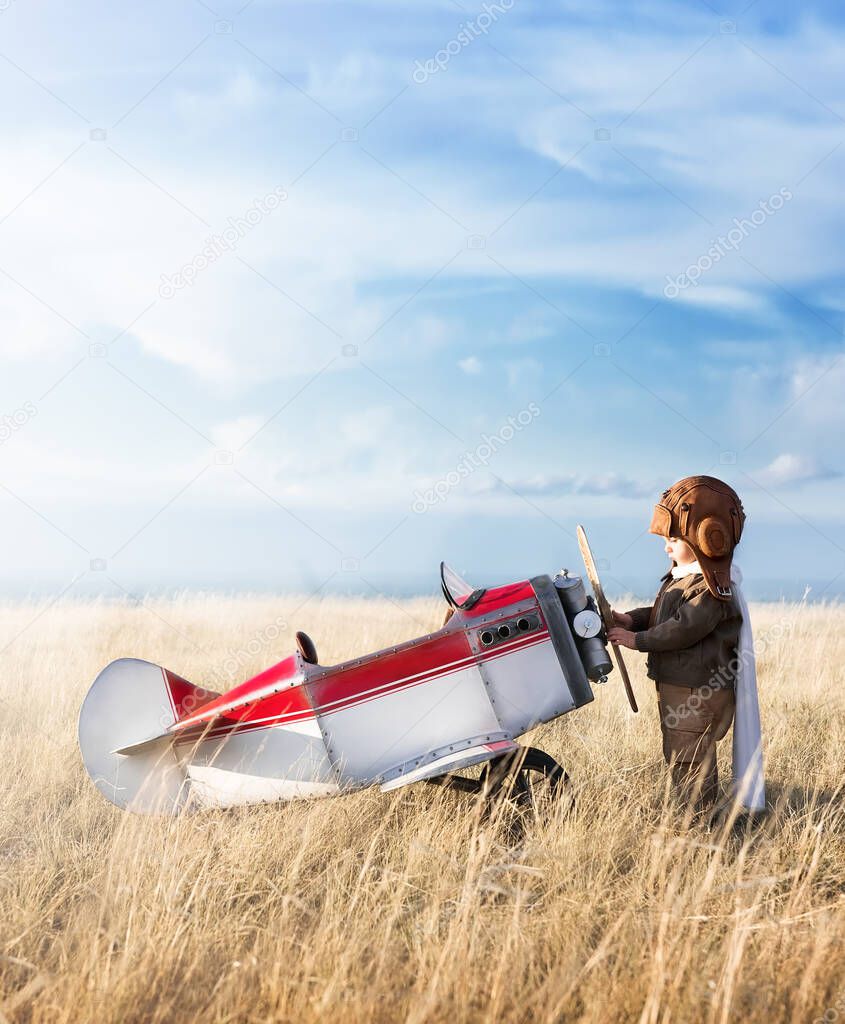 Young aviator with model airplane in the field on a sunny day