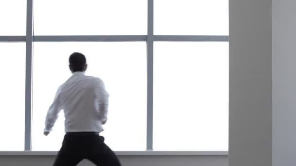 Business man dances near window . — стоковое видео
