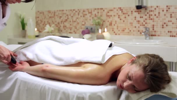 Mulher desfrutando de terapia de pedra. Feminino recebendo um tratamento de massagem relaxante — Vídeo de Stock