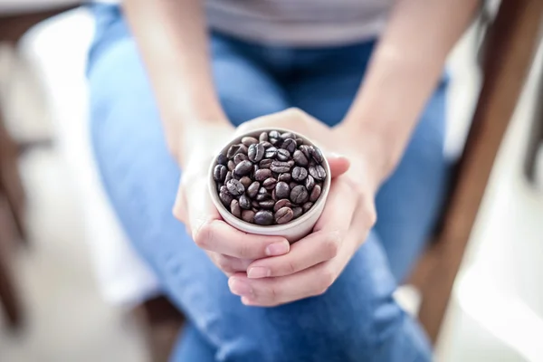 Koffieboon in beker op vrouw hand — Stockfoto