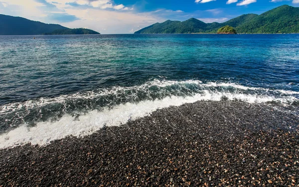 Belle mer cristalline avec plage de galets noirs — Photo