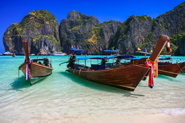 Long tail boat on white sand beach with crystal clear sea
