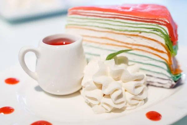 Rainbow crepe cake with a cup of strawberry juice