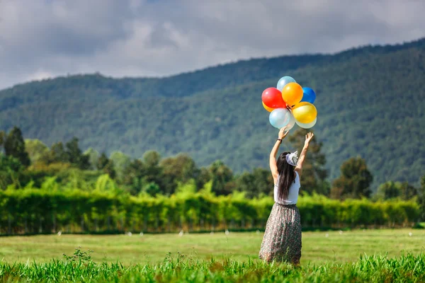 A girl playing balloon in grass field