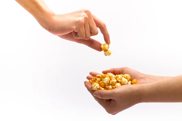 Mão pegando pipocas de caramelo encheu outra mão — Fotografia de Stock