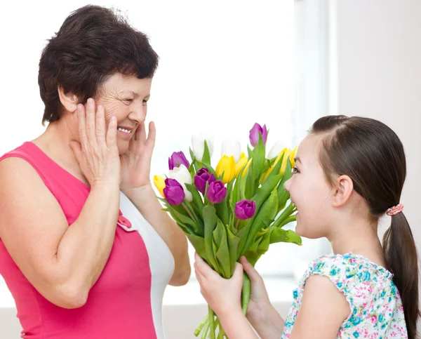 Grand-mère avec sa petite-fille. Femme et enfant avec bouquet de fleurs — Photo