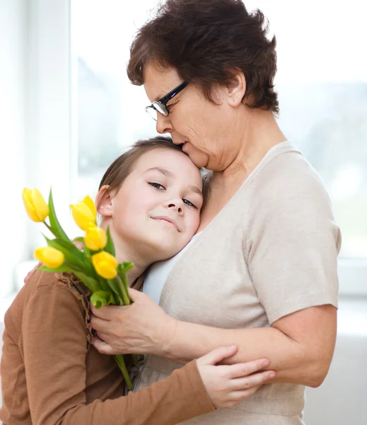 Бабушка с внучкой. Женщина и ребенок с букетом цветов — стоковое фото