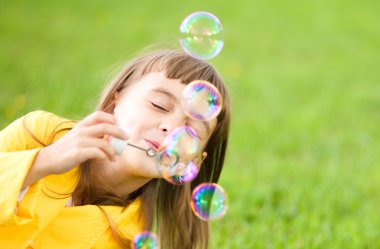 Küçük kız sabun köpüğü üflüyor