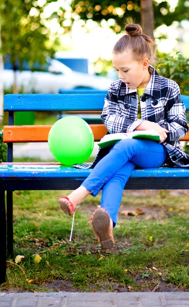 Liten flicka läser en bok utomhus — Stockfoto