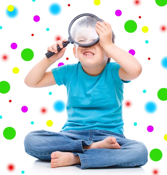 Cute little boy is playing with magnifier — Stock Photo, Image