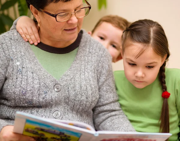 Grand-mère lit un livre avec ses petits-enfants — Photo