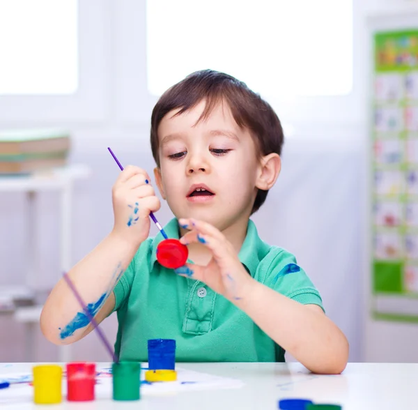 小さな男の子は塗料で遊んでいます。 ロイヤリティフリーのストック写真