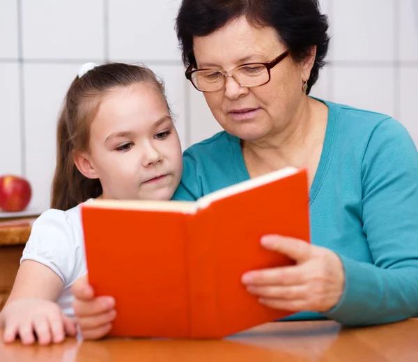 Grandmother is reading book with her granddaughter — Stock Photo, Image