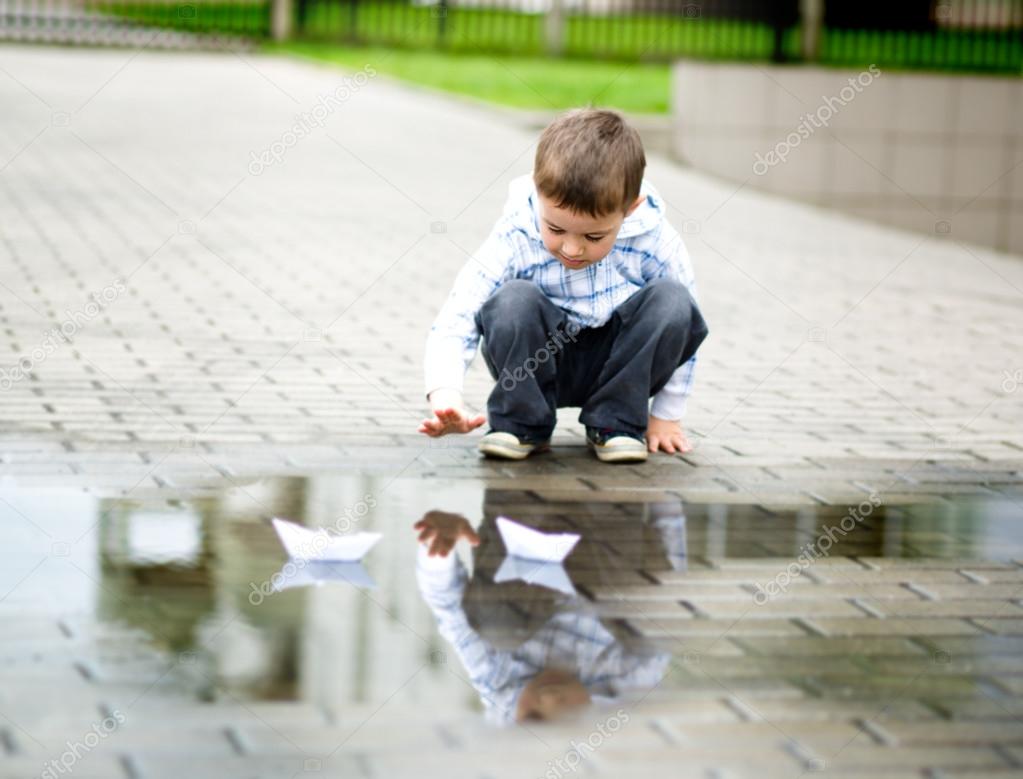 Boy is playing with paper boat