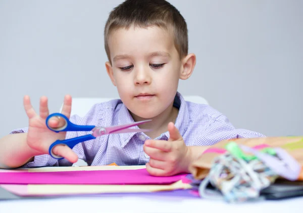 Menino está cortando papel usando tesoura — Fotografia de Stock