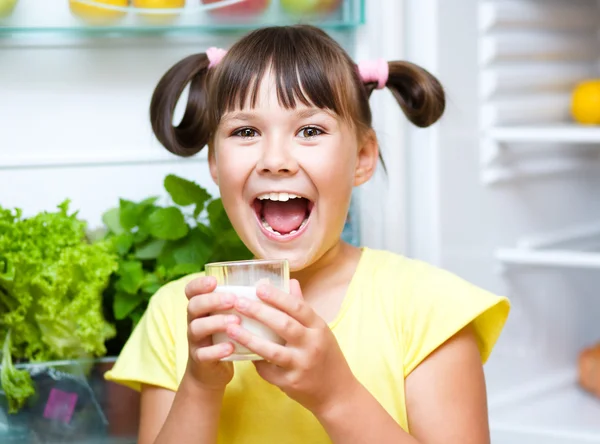 Chica beber leche de pie cerca del refrigerador —  Fotos de Stock