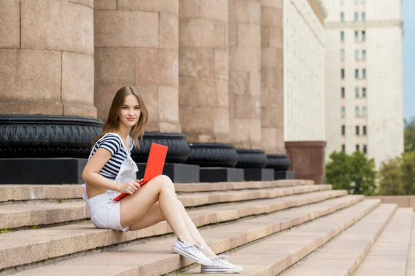 Giovane donna con computer portatile seduto sulle scale vicino all'università — Foto Stock