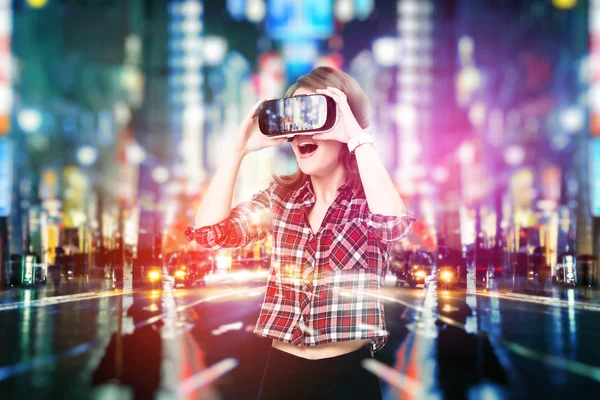 Двойная экспозиция, молодая девушка, получающая опыт работы в гарнитуре, использует очки дополненной реальности, находясь в виртуальной реальности. В городе ночью — стоковое фото