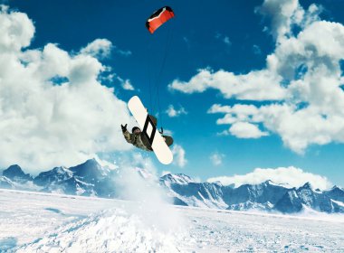 Genç, ata binip dağlarında yükselen güneş ışınlarının donmuş göl üzerinde kış snowboard