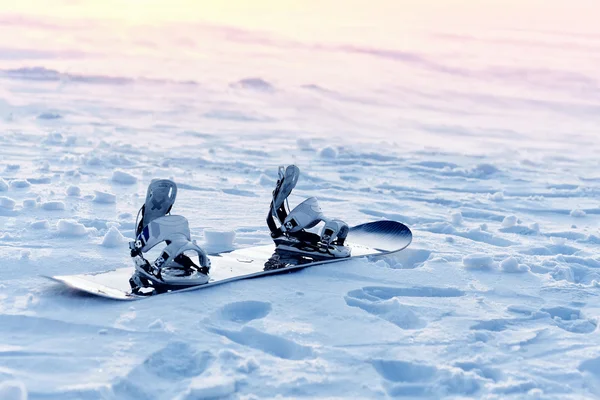 Karda gün batımında snowboard