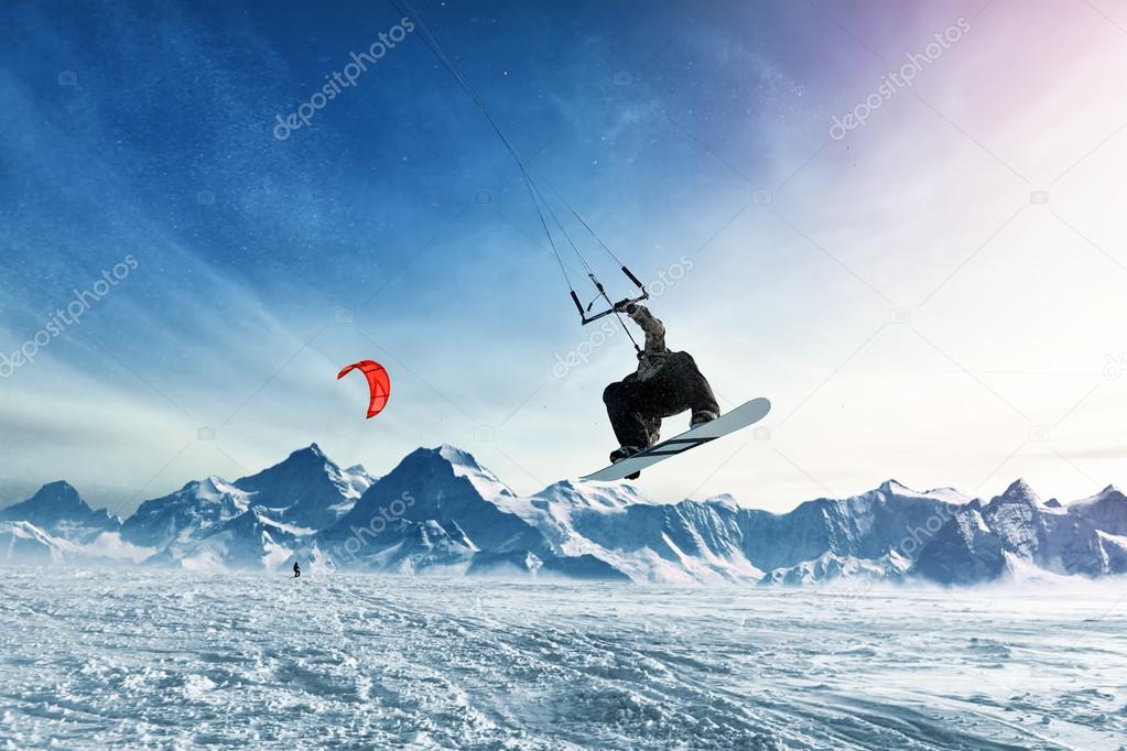 Young men, ride snowboarding on frozen lake in the mountains, in the rays of the rising sun, in winter