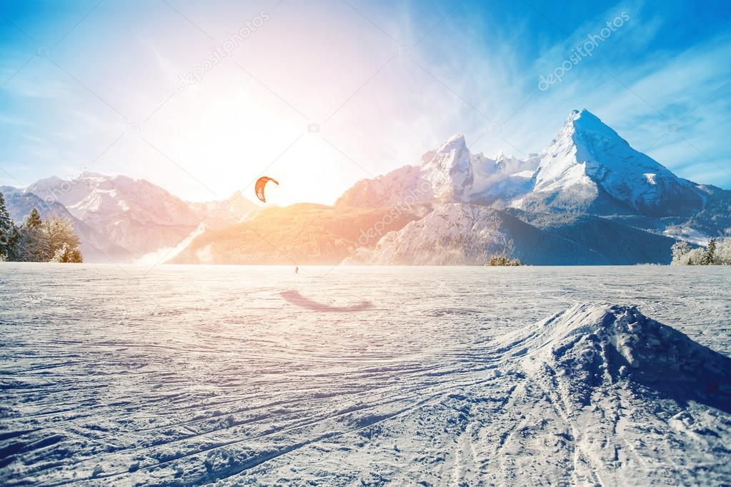 Young men, skiing on frozen lake in the mountains, in the rays o