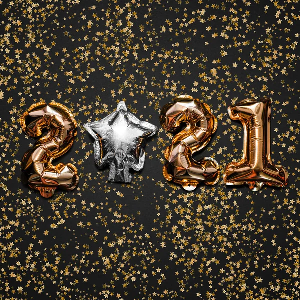 Happy New year 2021 celebration. Bright gold balloons figures, New Year Balloons with glitter stars on dark background. Christmas and new year celebration. Gold foil balloons 2021 gift card