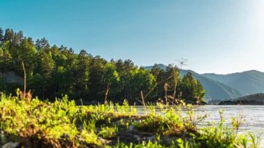 Zaman akışı bulutları nehir ve dağların üzerinden geçiyor. Zaman ayarlı. Yaz vadisi manzarası, nehir, tepeler, akan bulutlar. Ormandaki nehrin yakınındaki dağlarda günbatımı çok hızlı.