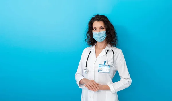 Doctor in het gezicht masker op felle kleur achtergrond maken gebaar hand. Meisje met beschermend gezichtsmasker covid-19. Banner medisch personeel preventief materiaal over coronavirus. Vrouw met medisch masker covid-2019 — Stockfoto