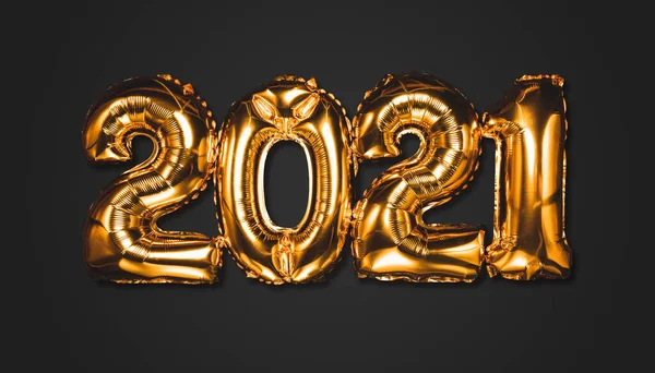 Bonne année 2021 célébration. Des ballons dorés brillants représentent des ballons du Nouvel An avec des étoiles scintillantes sur fond sombre. Noël et Nouvel An. Ballons en feuille d'or numéral 2021 et confettis — Photo