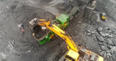 Açık maden ocağının yukarısından, üreme sıralaması, madencilik kömürü, çıkarma endüstrisi. Hareket halindeki şerit taşıyıcıdan kömür madenindeki kömür yığınına dökülen kömür madencileri arka planda çalışıyor.