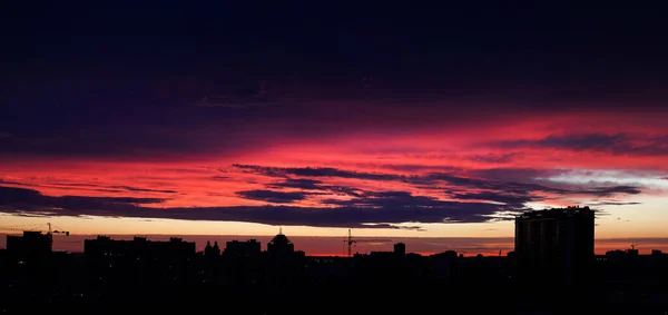 Panorama da altura ao pôr-do-sol na cidade. Bela vista da cidade nocturna. Vista do pôr do sol dos telhados da cidade. Céu nas nuvens ao pôr do sol — Fotografia de Stock
