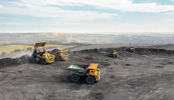 Large quarry dump truck. Big yellow mining truck at work site. Loading coal into body truck. Production useful minerals. Mining truck mining machinery to transport coal from open-pit production — Stock Photo, Image
