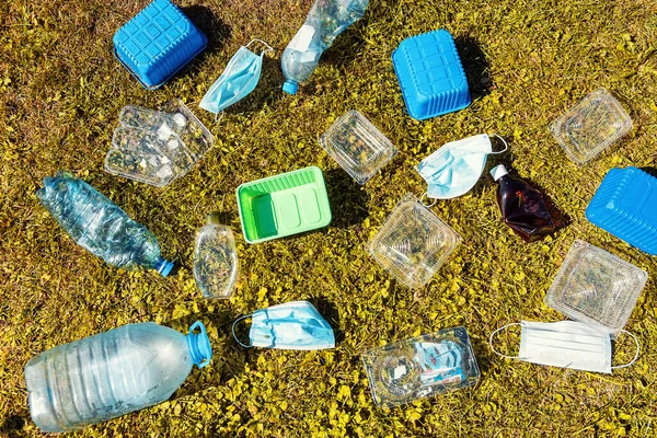 Мусор крупным планом. Много пластиковых отходов лежит в парке на траве. Пластиковый мусор на зеленой траве. Концепция ESG, ЦУР и экология. Упаковка для вторичной переработки Стоковое Фото