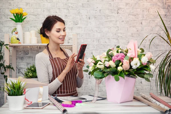Young woman florist at work. Business woman sale and floristry concept happy smiling woman making bunch at flower shop. Beautiful girl florist with flowers. Female florist working in from home