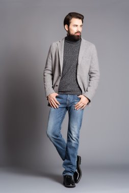 Bir ceket ve ayakta kot giyen genç adam sakallı,