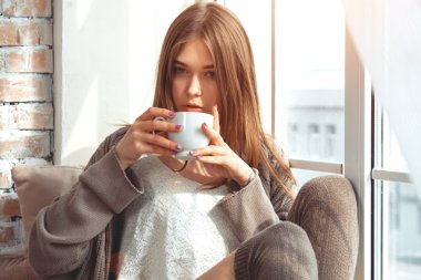 Bir pencere üzerinde oturan güzel genç kadın