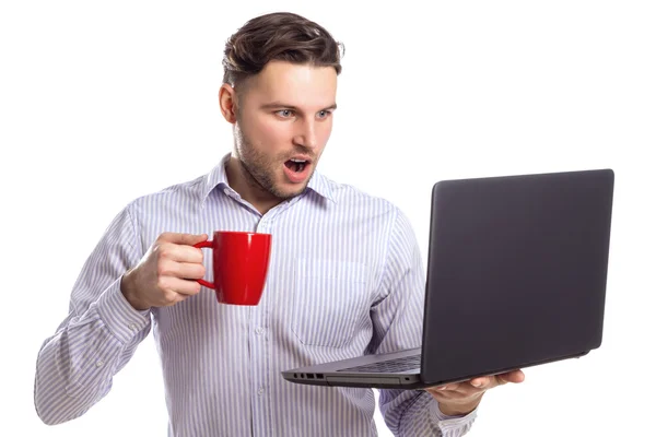 Όμορφος θυμωμένος επιχειρηματίας κρατώντας ερυθρό Κύπελλο και κοιτάζοντας το Laptop — Φωτογραφία Αρχείου