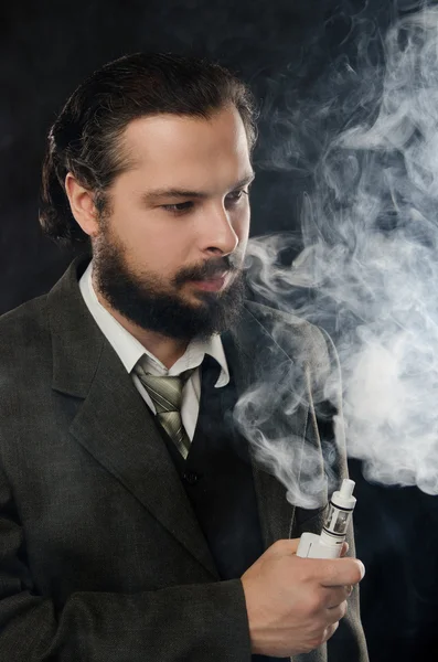 Hombre bien vestido fumar cigarrillo electrónico sobre fondo negro — Foto de Stock