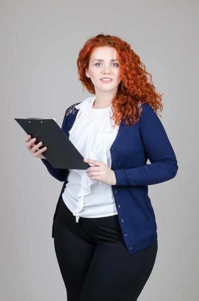 güzel şişko kız Kızıl saçlı tablet ile iş takım elbiseli ve gri arka plan üzerinde onun elinde kalem